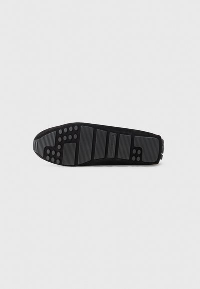 Black sneaker sole with textured rubber surface, featuring raised patterns and traction dots for grip and stability.