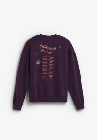 Sudadera morada con cuello redondo, dobladillo acanalado y texto impreso en la parte trasera que enumera las fechas y ubicaciones de la gira, con acentos decorativos.