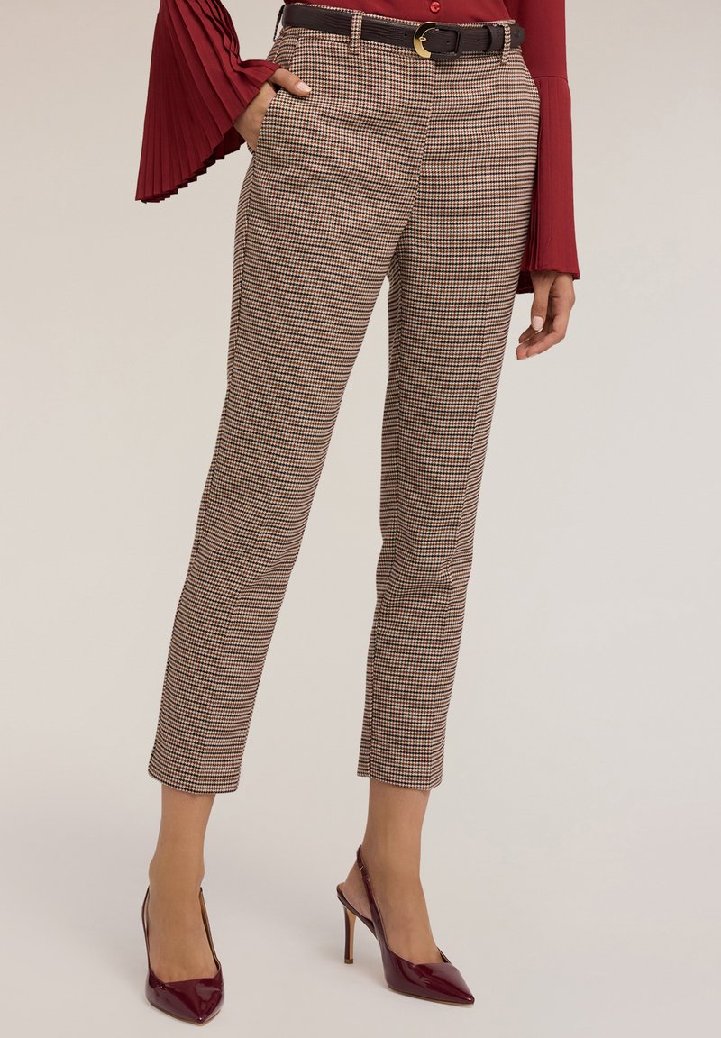 Pantaloni a quadri marroni e beige con vestibilità su misura, lunghezza cropped, tasche laterali e una cintura nera con fibbia dorata.