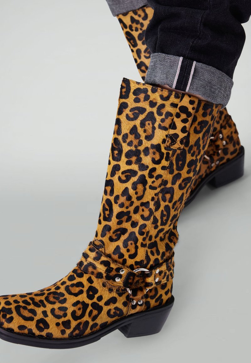 Leopardprint high-heeled laarzen met een gewolkte leren afwerking, voorzien van een band met metalen accenten en een puntige neus.