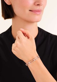 Pulsera de puño de plata que presenta dos bandas paralelas con tres pequeñas cuentas blancas espaciadas uniformemente. Diseño suave y minimalista con un acabado pulido.