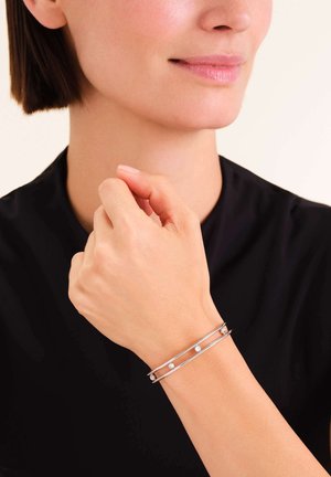 Pulsera de puño de plata que presenta dos bandas paralelas con tres pequeñas cuentas blancas espaciadas uniformemente. Diseño suave y minimalista con un acabado pulido.