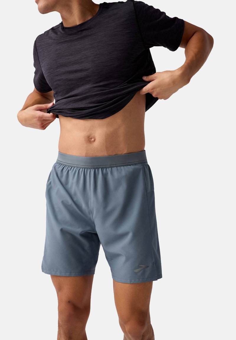 T-shirt de sport pour homme en noir et short en bleu clair, avec une taille élastique, un tissu léger et des poches latérales.