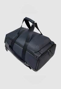 Donkerblauwe leren reistas met een gestructureerde afwerking, twee ritsvakken en twee schouderbanden. Stevige constructie en minimale accenten.