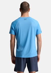 Hele sinine spordisärk lühikeste varrukatega, ümmarguse kaelusega ja tekstuurse kangaga, millel on väike logo ülemisel seljal.