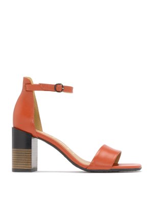 Sandale ouvert en cuir orange avec une bride de cheville et une boucle, talon bloc avec un détail en bois, et semelle noire sur fond blanc.