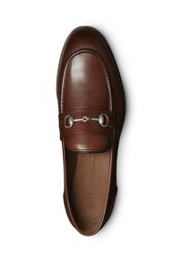 Mocassin en cuir marron avec un bout arrondi, accent métallique à l'avant et surpiqûres détaillées. Texture lisse avec un design minimaliste.