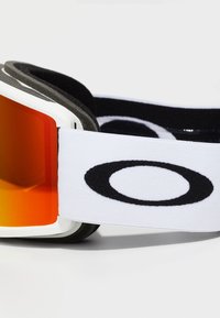 Lunettes de ski blanches avec des verres orange, rembourrage en mousse noire et une sangle blanche arborant un logo noir. Monture en plastique lisse avec des bords arrondis.
