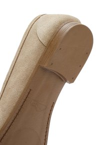 Scarpa in camoscio beige con forma curvata, caratterizzata da una suola in pelle liscia e piccole scanalature circolari per una migliore aderenza. Cuciture decorative lungo il bordo.