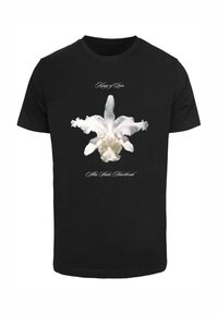 Sort bomulds T-shirt med et stort hvidt orkidé grafik med flagrende kronblade, prydet med dekorativ tekst over og under blomsten.