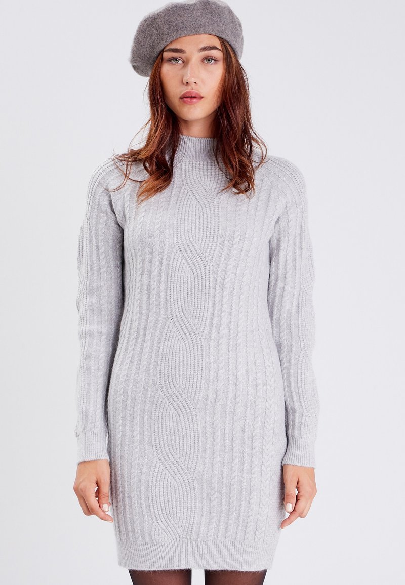 Vestido de punto acanalado gris claro con cuello alto, que presenta cables texturizados. Mangas largas con puños ajustados. Tejido suave y cómodo.