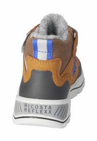 Botín infantil marrón y gris con un interior suave, correa de Velcro y suela de goma texturizada, con acentos en azul y blanco.