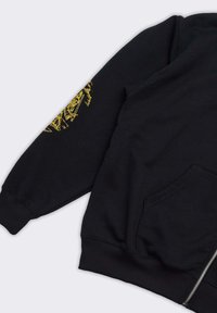 Felpa nera con chiusura a zip e polsini a costine. Design grafico giallo sulla manica sinistra che aggiunge un accento distintivo.