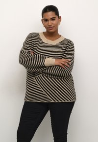 Raidalline neuletakki beige ja musta. Varustettu leveillä raidoilla, ribbaamalla kauluksella ja hihoilla. Pehmeä rakenne rentoon istuvuuteen.