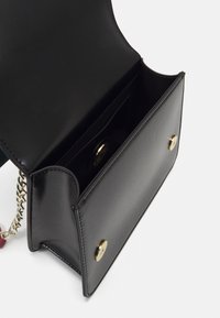 Borsa a tracolla in pelle nera con hardware dorato, caratterizzata da una tracolla in catena, una tasca interna e una texture liscia. Vista aperta che mostra l'interno.