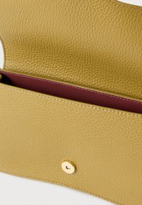 Carteira amarela de couro com superfície texturizada e interior cor de vinho. Apresenta um fecho de pressão dourado e detalhes de costura visíveis.