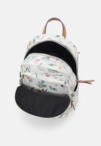 Sac à dos à motif floral en blanc avec des feuilles vertes et des fleurs colorées. Il dispose de deux compartiments zippés et d'accents en cuir marron.