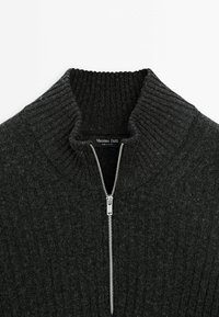 Pull en maille côtelée gris foncé avec une demi-fermeture éclair argentée et un col montant, étiquette de marque Massimo Dutti visible à l'intérieur de l'encolure.