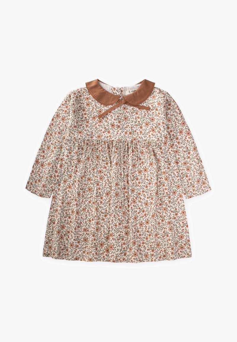 Lilledega pluus, pikkade varrukatega, beežist kangast, millel on väiksed oranžid lilled, pruuni satiinist kaeluse ja vöökoha klappidega.