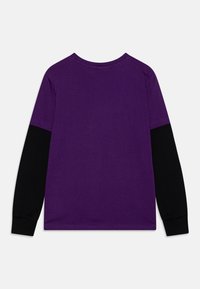 Langermet t-skjorte med en lys lilla kropp og svarte ermer, laget av myk bomull, med rund hals og enkel sømdetalj.