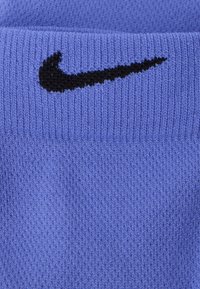 Μπλε πλεκτό ύφασμα με ριμπ υφή που διαθέτει μαύρο λογότυπο Nike. Το ύφασμα φαίνεται μαλακό και έχει ομοιόμορφο χρώμα σε όλο του το μήκος.