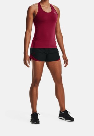Punainen urheilutankkitoppi, jossa on hihaton malli, yhdistetty mustiin shortseihin, joissa on punaiset yksityiskohdat. Yllä mustat urheilukengät.