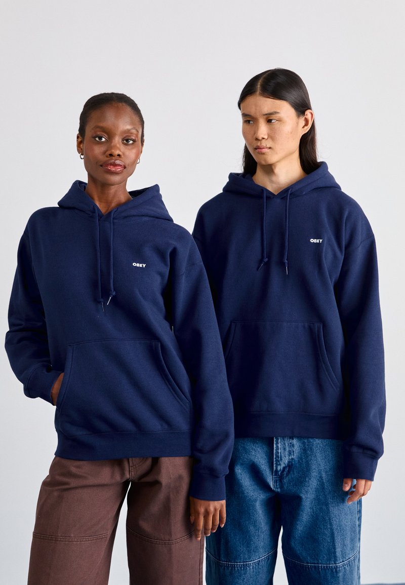 Sweatshirts azul-marinho com bolso frontal e cordões; apresentam o logotipo branco "OBEY" no peito; tecido misto, corte descontraído.