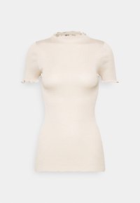 Cream-colored short sleeve ribbed knit top with mock neck and ruffled edges on sleeves and collar.