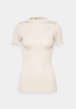 Cream-colored short sleeve ribbed knit top with mock neck and ruffled edges on sleeves and collar.