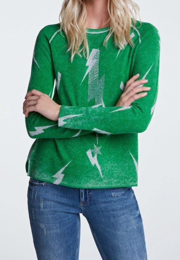 Pull vert avec un motif d'éclair gris. Présente un col rond et une coupe décontractée, porté avec un jean bleu. La texture semble douce.