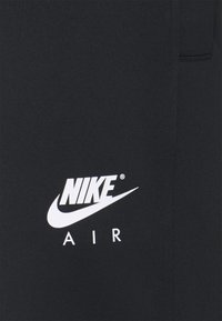 Černé sportovní šortky s bílým logem Nike Air. Design je jednoduchý, s hladkým texturem a standardním střihem.