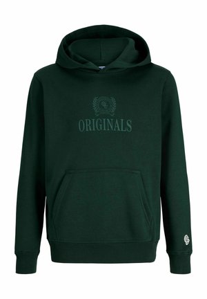 Enfant blond portant un sweat à capuche vert foncé avec le texte « Originals », un jean large bleu foncé et des chaussures beiges, regardant vers la droite sur un fond blanc.