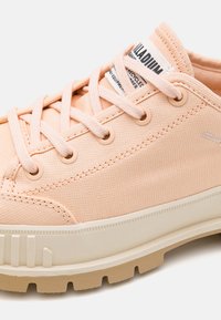 Sneaker bassa color pesco chiaro con tomaia in tessuto, suola in gomma crema, lacci coordinati, occhielli in metallo e etichetta con marchio sulla linguetta.