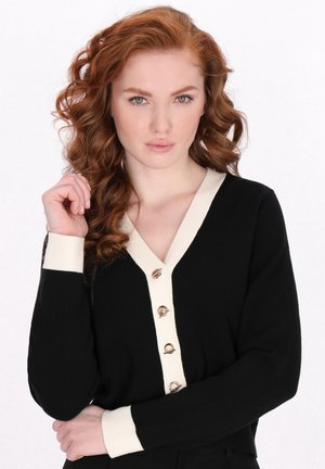 Cardigan nero con dettagli crema, design a V, sei bottoni dorati sul davanti e polsini a coste. Texture morbida, silhouette aderente.