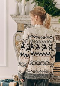 Cremefarbener Strickpullover mit Rentiermustern, ausgestattet mit schwarzen und braunen geometrischen Akzenten, gerippten Bündchen und einem hohen Kragen.