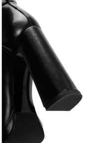 Černé lodičky na vysokém podpatku s silným, cylindrickým podpatkem. Vyrobené z hladké kůže s elegantním povrchem. Disponují minimalistickým designem a bez ozdob.