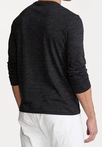 Langärmliges Shirt aus dunkelgrauem Stoff mit meliertem Muster. Runder Halsausschnitt und enganliegende Ärmel, mit lockerem Sitz in der Taille.