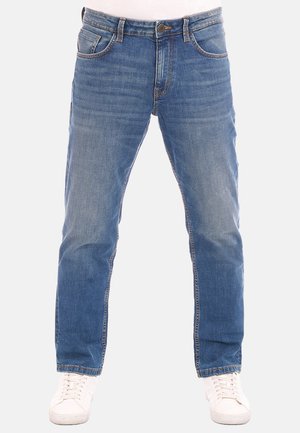Vaqueros de mezclilla azul claro con un diseño de pierna recta, que cuentan con cinco bolsillos, un sutil desvanecimiento y costuras en contraste. Llevados con zapatillas blancas.