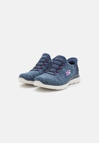 Scarpe da ginnastica blu navy con tomaia in tessuto testurizzato, lacci elastici, leggera ammortizzazione e suola in gomma bianca con dettagli viola.