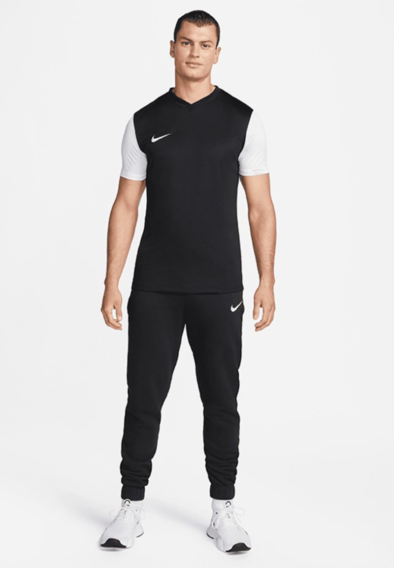 Schwarzes Sport-T-Shirt mit weißen kurzen Ärmeln und V-Ausschnitt. Kombiniert mit schwarzen Jogginghosen mit elastischen Bündchen und Nike-Logo.