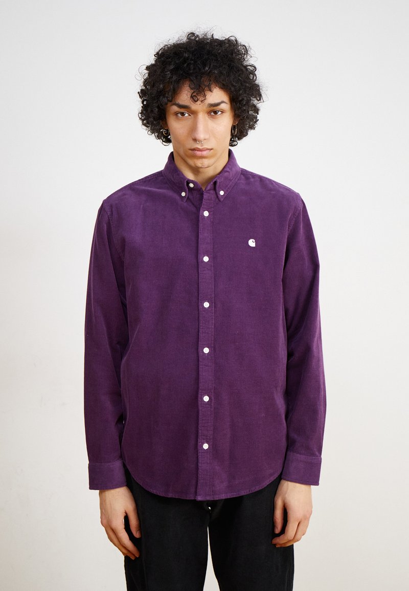 Paarse corduroy overhemd met een button-down kraag, witte knopen en een klein wit logo op de linkerborst. Lange mouwen met knoopmanchetten.