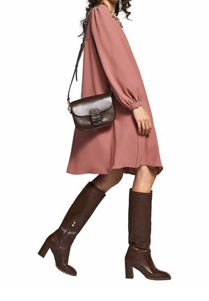 Ruskeat polveen ulottuvat nahkasaappaat, vaaleanpunainen pitkähihainen mekko ja ruskea olan yli kannettava laukku. Sileä pinta, yksinkertainen muotoilu ja suora siluetti.