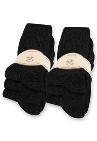 Schwarze knielange Socken, gerippte Textur, weiches Material. Verpackung mit vier Paar Socken, mit einem Etikett, das ein Schaf-Logo und Pflegehinweise zeigt.