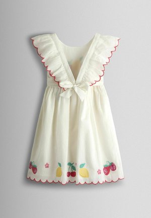 White cotton dress with ruffled shoulders, scalloped edges, and a tied bow. Features colorful fruit embroidery at the hem and textured fabric.