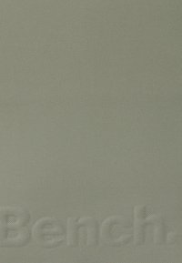 Lichtgroene stof met een textuurafwerking, met een reliëf 'Bench.' logo in de linkerbenedenhoek.