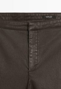 Donkerbruine leren broeken met een gestikt tailleband en een klein "Massimo Dutti Made in Morocco" label aan de binnenkant.