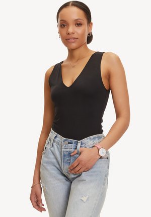 Body a maniche corte nero con scollatura a V, realizzato in tessuto liscio, abbinato a jeans dal taglio alto e sbiaditi di colore blu chiaro.