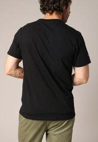 T-shirt en coton noir avec un col rond et des manches courtes, vu de dos. Présente une texture lisse et une coupe légèrement ample.