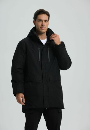 Schwarze wasserdichte Jacke mit Kapuze, zwei mit Reißverschluss versehenen Brusttaschen, vorderen Klapptaschen und verstellbaren Bündchen. Minimalistisches Design.