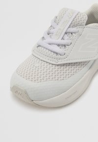 Vaaleanharmaat New Balance -lenkkarit, joissa on verkkopinta, valkoiset nauhat ja "Fresh Foam" -pehmustettu pohja, esillä valkoista taustaa vasten.